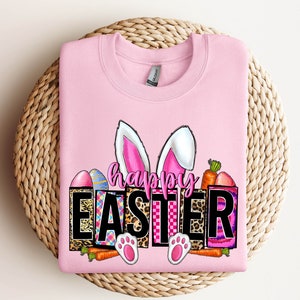 May include: Pink sweatshirt with a graphic design of bunny ears, carrots, and Easter eggs. The graphic says "Happy Easter" in black letters.