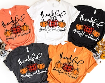 May include: Five t-shirts with a Thanksgiving theme. The shirts are in various colors, including orange, white, black, and gray. Each shirt features a graphic of pumpkins with the text "thankful grateful & blessed".