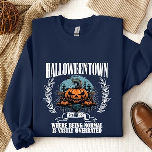 Może przedstawiać: Granatowa bluza z nadrukiem dyni i tekstem "HALLOWEENTOWN EST. 1998 WHERE BEING NORMAL IS VASTLY OVERRATED".