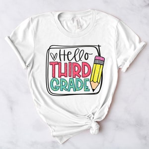 May include: White t-shirt with a graphic design that says "Hello Third Grade" with a pencil illustration.