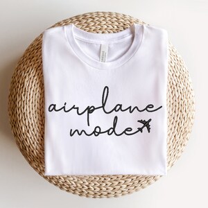 May include: White t-shirt with black text that says "airplane mode" with a small airplane icon.