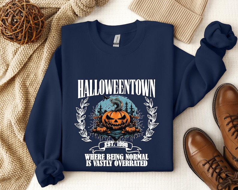 Może przedstawiać: Granatowa bluza z nadrukiem dyni i tekstem "HALLOWEENTOWN EST. 1998 WHERE BEING NORMAL IS VASTLY OVERRATED".