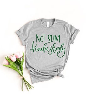 May include: Gray t-shirt with the text "Not Slim Kinda Shady" in green lettering.