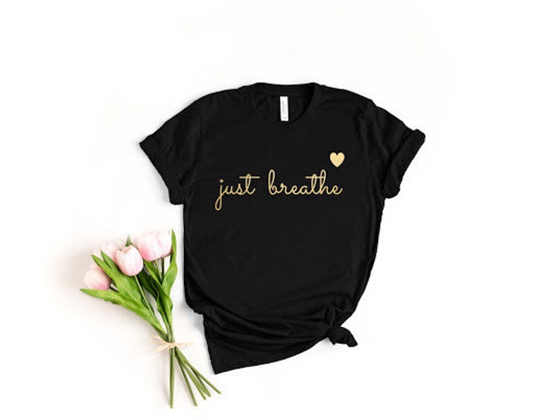 May include: Black t-shirt with the text "just breathe" in gold lettering and a small gold heart above the text.