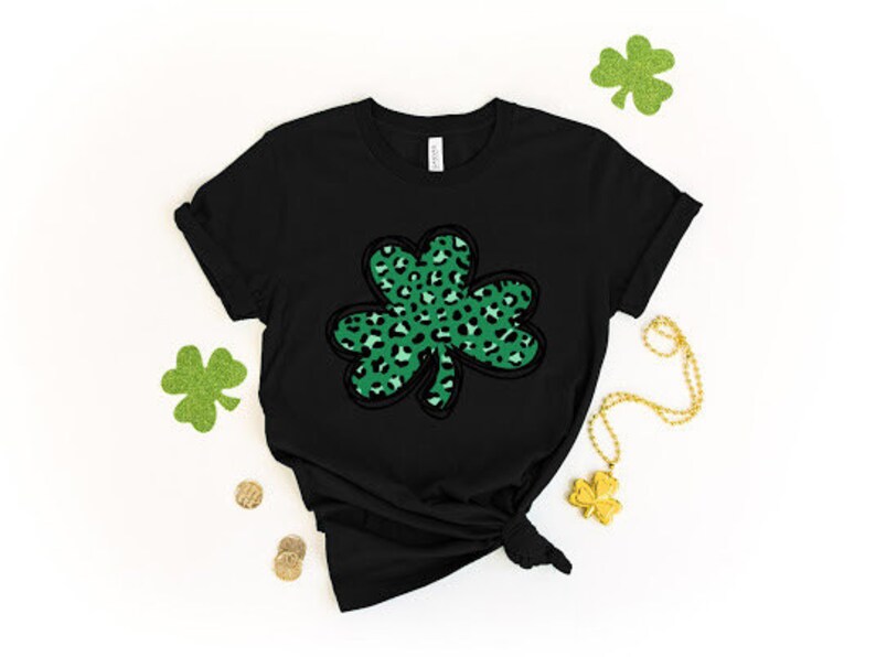 May include: Black t-shirt with a green and black leopard print shamrock design.