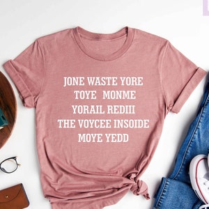 May include: A heather mauve t-shirt with the text "Jone waste yore toye monme yorail rediii the voycee insoide moye yedd" printed in white.