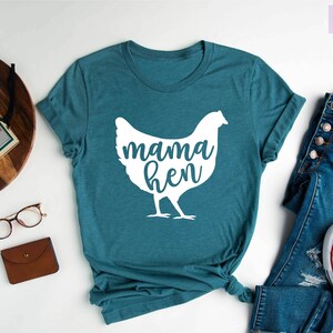 May include: A teal blue t-shirt with a white silhouette of a chicken and the text "mama hen".