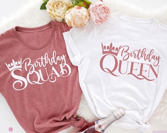 May include: Two t-shirts, one heather mauve and one white, with the text "Birthday Squad" and "Birthday Queen" printed on them. The shirts are laid out on a white fuzzy surface with a bottle of sparkling wine.