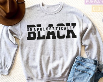 May include: A gray sweatshirt with the text "Unapologetically Black" printed in black on the front.