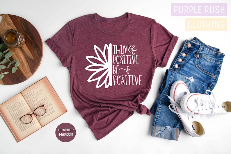 May include: A maroon heather t-shirt with a white graphic of a sunflower and the text "Think Positive Be Positive".