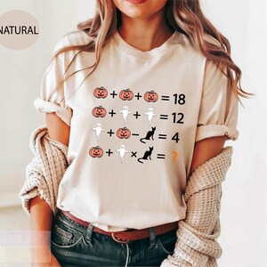 a woman wearing a white t - shirt with a halloween graphic on it
