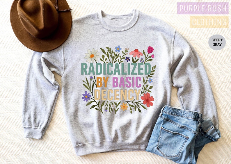 a gray sweatshirt with a colorful graphic design, a brown hat, and a pair of blue jeans, all laid out on a white surface.