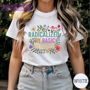 A woman wearing a white t-shirt with a colorful graphic design and text printed on it.