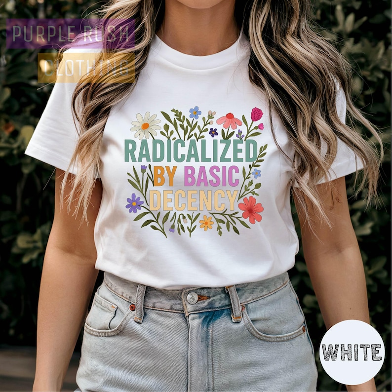 A woman wearing a white t-shirt with a colorful graphic design and text printed on it.