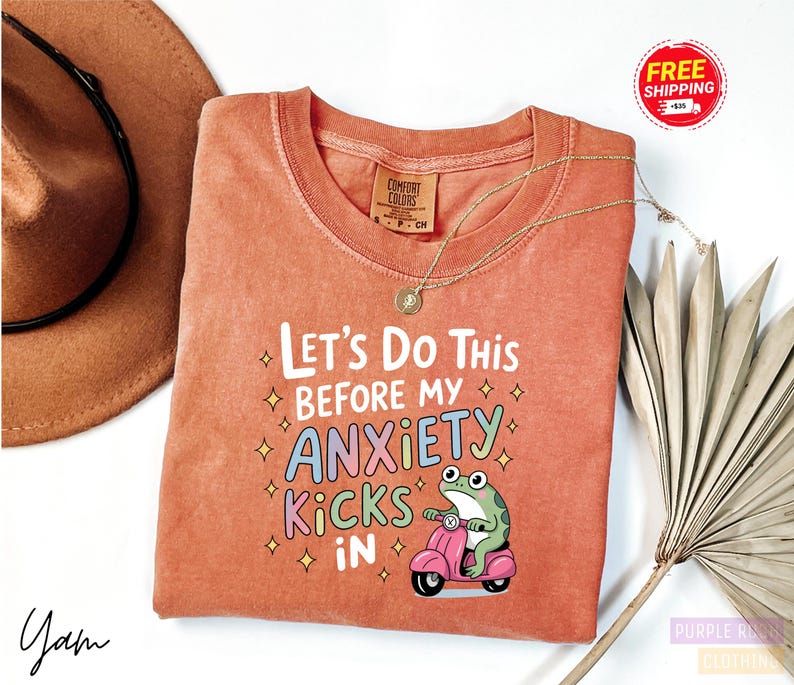 a red t-shirt with a humorous text and an illustration of a frog riding a motorcycle.