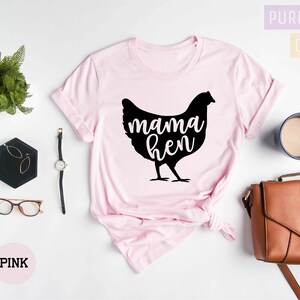 May include: A pink t-shirt with a black silhouette of a chicken and the text "mama hen" printed on the front.