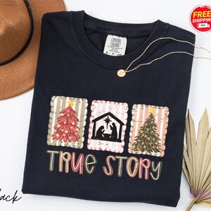 Camiseta navideña con historia real, camiseta con escena de la Natividad cristiana, camiseta con colores que inspiran consuelo religioso, camiseta navideña del nacimiento de Jesús, camiseta con valores religiosos