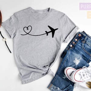May include: A grey t-shirt with a black airplane and heart design. The text "Purple Rush Clothing" and "Athletic Heather" is visible in the image.