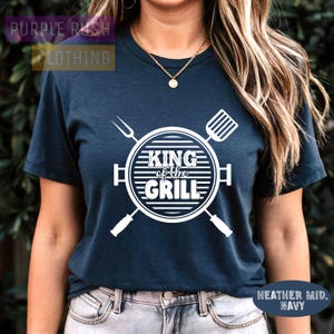 May include: A navy blue t-shirt with a white graphic of grilling tools and the text "King of the Grill".