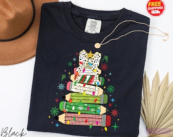 May include: Black crew neck sweatshirt featuring a Christmas tree design made of pencils. The tree is decorated with lights, a star, and a bow. The word "Black" is printed on the bottom left.