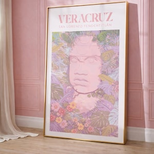 Puede incluir: Un cuadro enmarcado con la palabra "VERACRUZ" y el texto "SAN LORENZO TENOCHTITLÁN". La obra de arte representa una escultura de cabeza olmeca rosa rodeada de flores y follaje coloridos. El marco es dorado.
