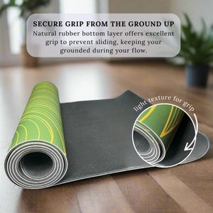 May include: A partially unrolled yoga mat with a green and yellow circular design. The mat has a black underside and a light texture for grip. Text on the image reads "SECURE GRIP FROM THE GROUND UP".