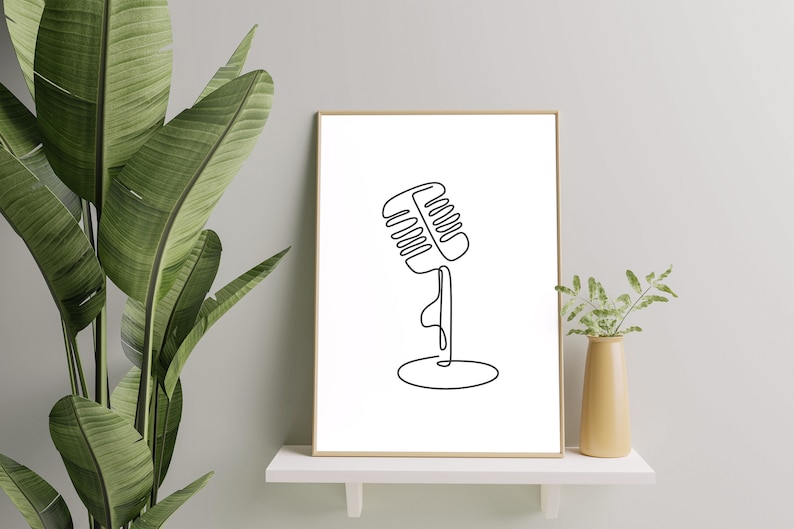 May include: A black and white line drawing of a vintage microphone on a stand, framed in a simple wooden frame. The drawing is on a white background.