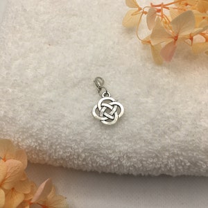 Könnte beinhalten: Silberner Anhänger mit einem keltischen Knotendesign. Der Knoten ist eine durchgehende Schleife, die Ewigkeit und Einheit symbolisiert.