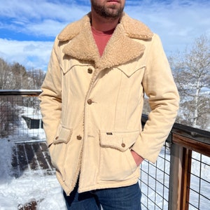 May include: A cream-coloured corduroy jacket with a brown faux fur collar and brown buttons. The jacket has two large pockets on the front and a small pocket on the left chest. The jacket is made by the brand "Levi's".