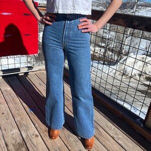 May include: A pair of blue denim wide-leg jeans with a high waist and a button fly.