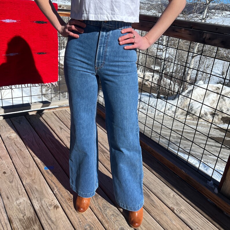 May include: A pair of blue denim wide-leg jeans with a high waist and a button fly.