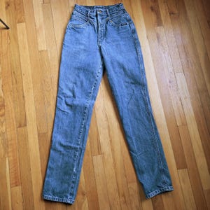May include: Light blue denim jeans with a high waist and straight leg. The jeans have a button and zipper closure, with pockets in the front and back. The jeans are made of a sturdy denim material.