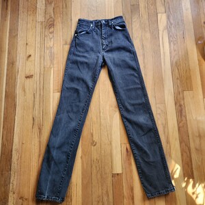 May include: A pair of black denim jeans with a button fly and classic five-pocket design. The jeans have a high waist and a straight leg, suitable for various styles. The dark wash adds a versatile, timeless appeal.