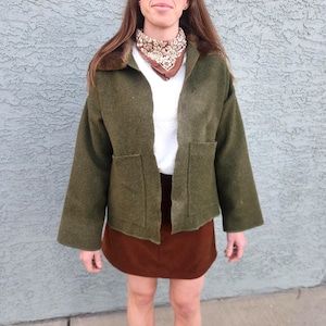 Chaqueta tipo manta militar vintage de lana verde hecha a mano, con cuello de piel sintética y parche floral. Talla mediana.