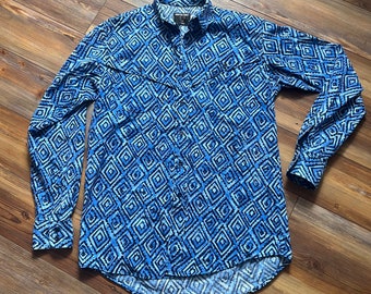 May include: A long-sleeved button-down shirt with a geometric diamond pattern in shades of blue and white. The shirt has two chest pockets and a classic collar. The fabric appears to be a lightweight material.