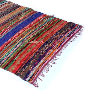 May include: A colorful, striped rug with a variety of colors including red, blue, green, and orange. The rug has a fringed edge and the text "BismilRugs" is visible. The rug is made of woven fabric.