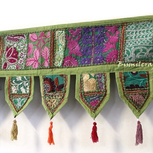 May include: A green patchwork fabric valance with a scalloped bottom and tassels. The valance is made of different fabrics with floral and geometric patterns in shades of green, pink, purple, and gold. The valance is labeled "Bismilcraft".