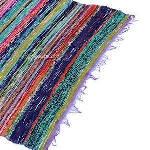 May include: A colorful, striped rug with a variety of colors including blue, green, orange, and pink. The rug has a textured appearance and a fringed edge. The diagonal stripes create a dynamic visual effect. The rug is likely made of fabric.