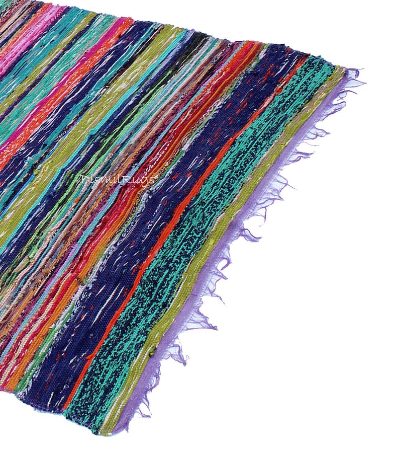 May include: A colorful, striped rug with a variety of colors including blue, green, orange, and pink. The rug has a textured appearance and a fringed edge. The diagonal stripes create a dynamic visual effect. The rug is likely made of fabric.