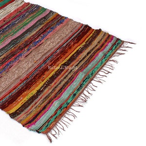 May include: A colorful, striped rug with a variety of colors including red, orange, green, and brown. The rug has a fringed edge and the text "Bismil Rugs" is visible. The rug is made of woven fabric.