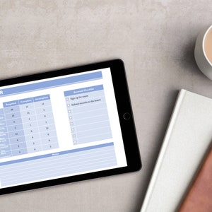 May include: A blue tablet with a checklist for renewal requirements. The checklist includes items like "Sign up for exams" and "Submit records to the board". The tablet is on a gray surface with a white notebook and a brown leather journal.