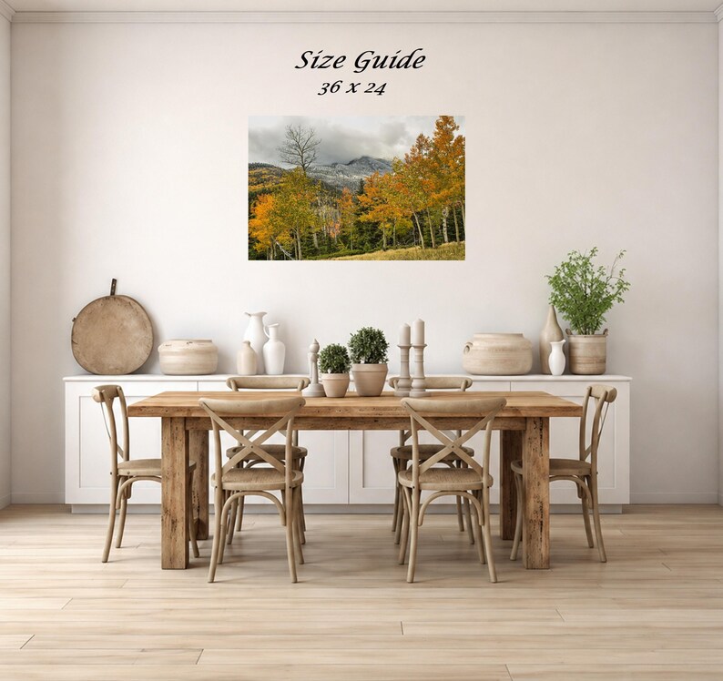 Mockup of a 36 by 24 inch autumn mountain landscape print displayed on a dining room wall above a wooden table.