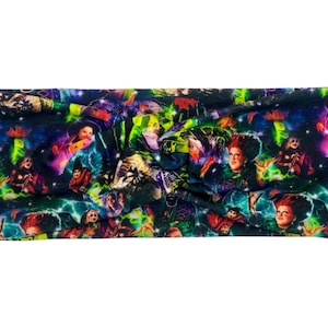 May include: A colorful headband featuring a repeating pattern of characters from a Halloween-themed movie. The design includes images of witches, pumpkins, and a starry night sky. The headband is made of a soft, stretchy fabric.