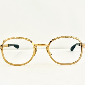 May include: Gold-tone round eyeglasses with a braided metal frame.