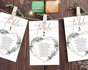 May include: Three white table cards with gold calligraphy that says "table" and a number. Each card has a gold geometric heart shape with a green olive branch and blue berries. The cards list names for each table.