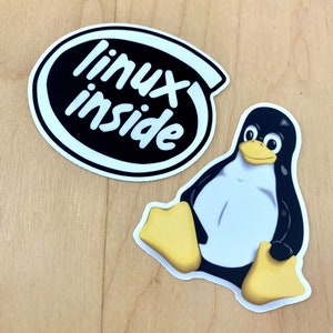 May include: Two stickers, one black and white with the text "linux inside" and the other a cartoon penguin with a white belly and yellow feet.