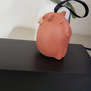 May include: A terracotta-colored ceramic animal figurine with a cork stopper. The figurine is shaped like a pig and has a brown cork stopper in the back.