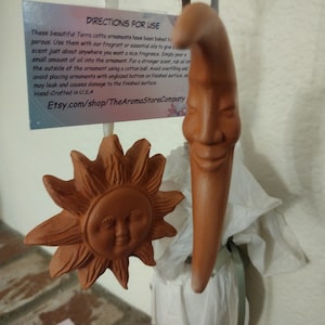 May include: Terracotta sun and moon ornaments with smiling faces.  These ornaments are porous and can be used with essential oils to add fragrance to any room.  Directions for use are included on the card.  Etsy.com/shop/TheAromaStoreCompany