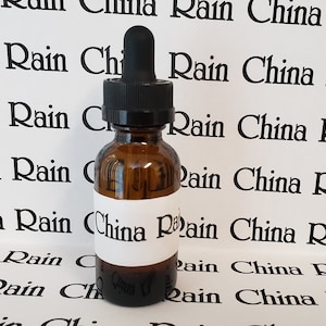 May include: A clear glass bottle with a dropper top and a white label that says "China Rain". The bottle is sitting on a white surface with the words "China Rain" repeated in black.