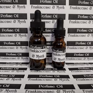 May include: Two amber glass perfume oil bottles with black droppers. The bottles have white labels with the text "Perfume Oil Frankincense & Myrrh". The background features repeating labels with the same text.